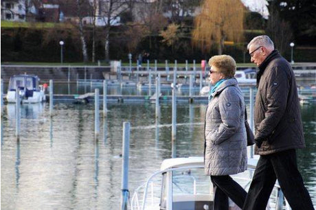 senior couple holding hands walking by dock