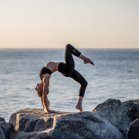Woman doing yoga on rock beach