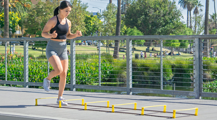 Woman performing agility ladder drills outdoors for speed, coordination, and footwork training.