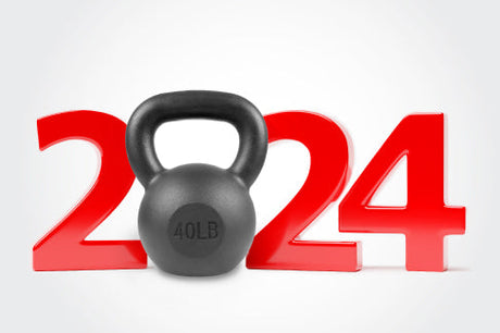 Black 40LB kettlebell placed in front of large red numbers forming ‘2024,’ symbolizing New Year fitness goals.