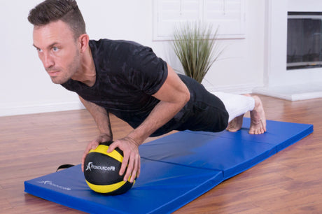 man doing a plank on prosourcefit rubber medicine ball and prosourcefit tri-fold folding mat 