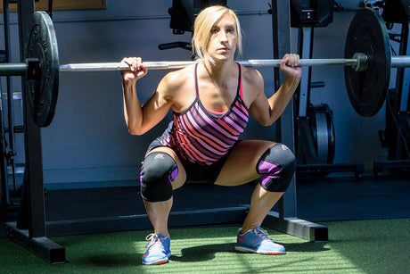 Fit woman using Woman using ProsourceFit barbell, bumper plates and knee sleeves while in a barbell squat