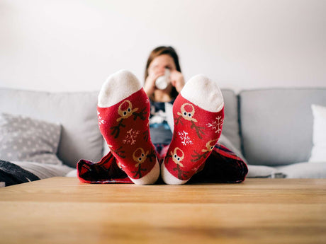 woman wearing red christmas socks with feet on coffee table